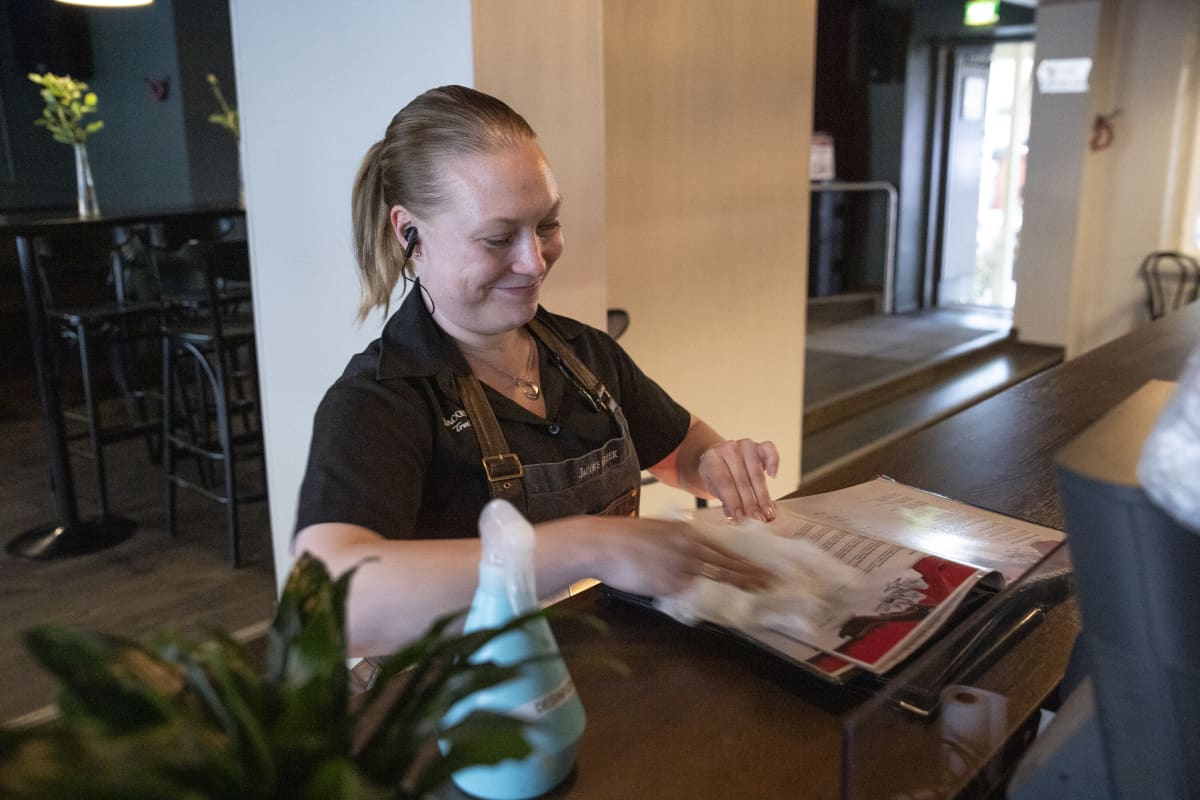 tarjoilija Minna laukkanen desinfioi ruokalistoja asiakkaiden käytön jälkeen ravintola Kummisdässä Kuopiossa
