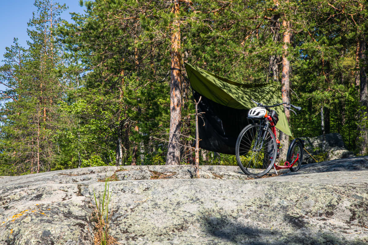 Riippumatto ja potkupyörä luonnossa järven rannalla.