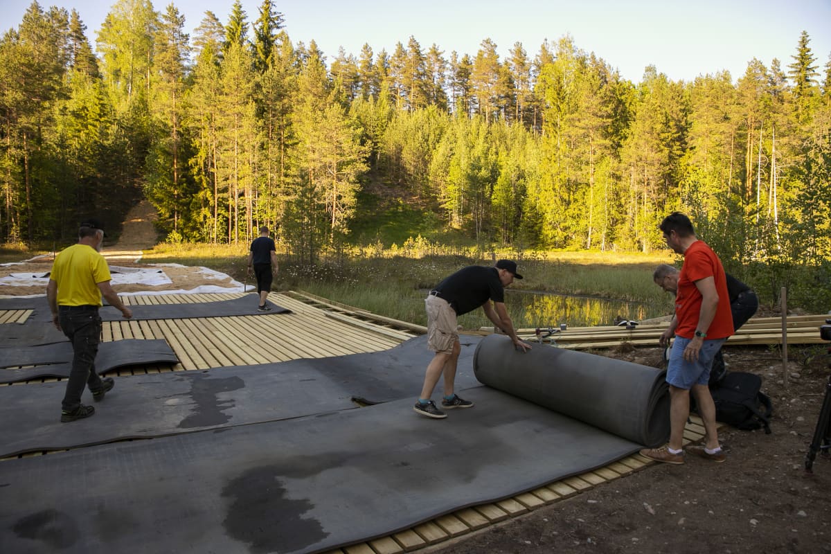 Miehiä levittämässä pehmustetta mäkihyppyrimäen alastuloon Janakkalan Leppäkosken hyppyrimäellä.