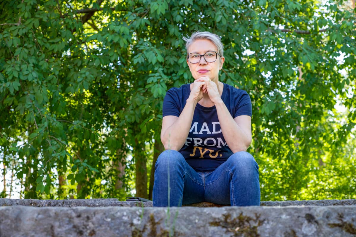 Varpu Marjomäki istuu kivestä tehdyllä istuimella.