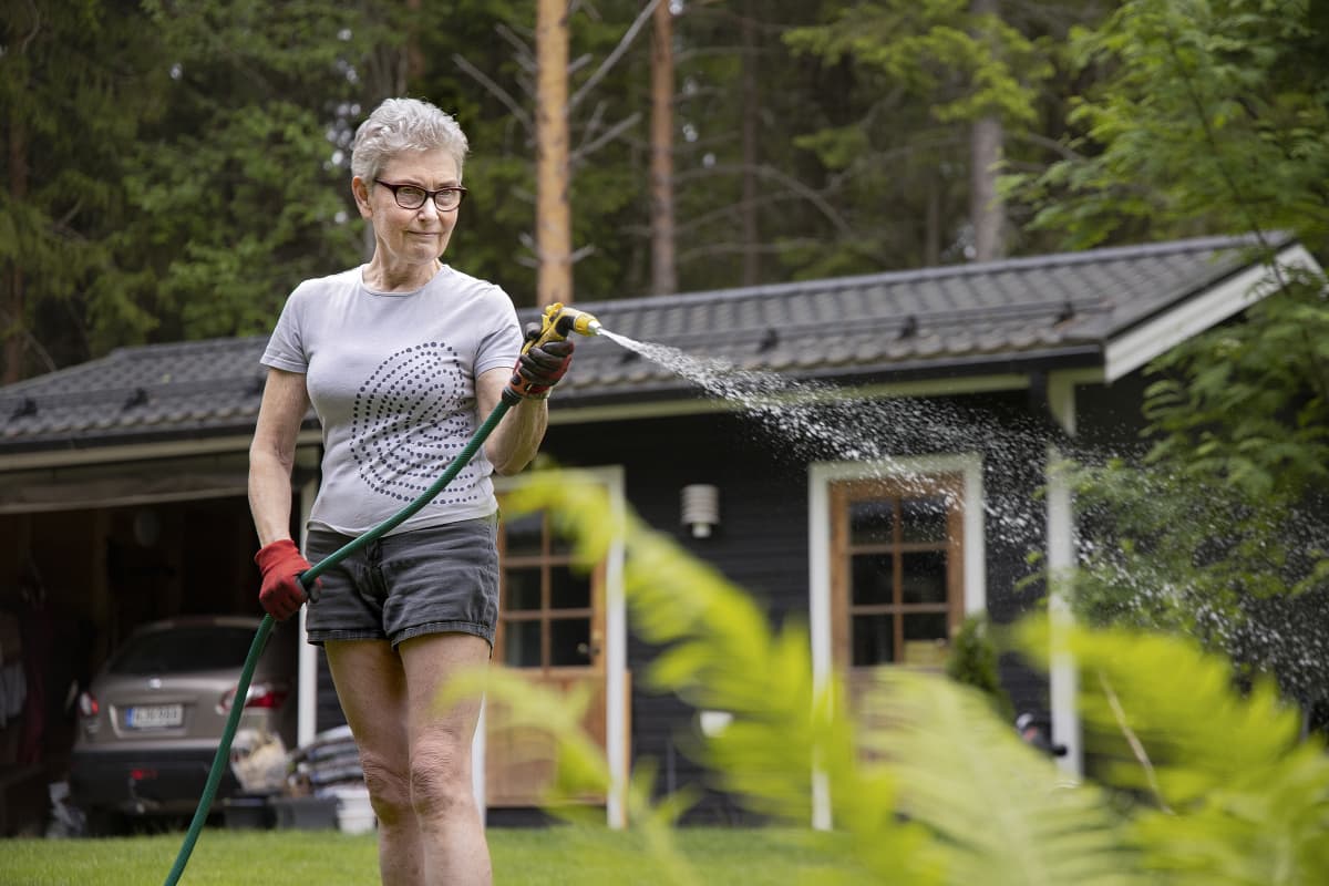 Pirjo-Leena Pitkänen kastelee kukkia.