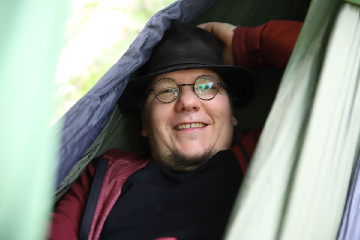 Hattupäinenmies makaa riippumatossa hymyillen.