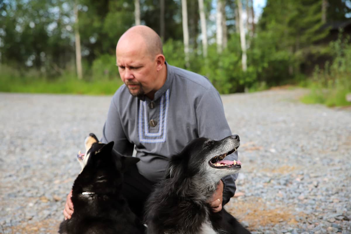 Kaksi mustaa porokoiraa nauttii omistajansa rapsutuksista
