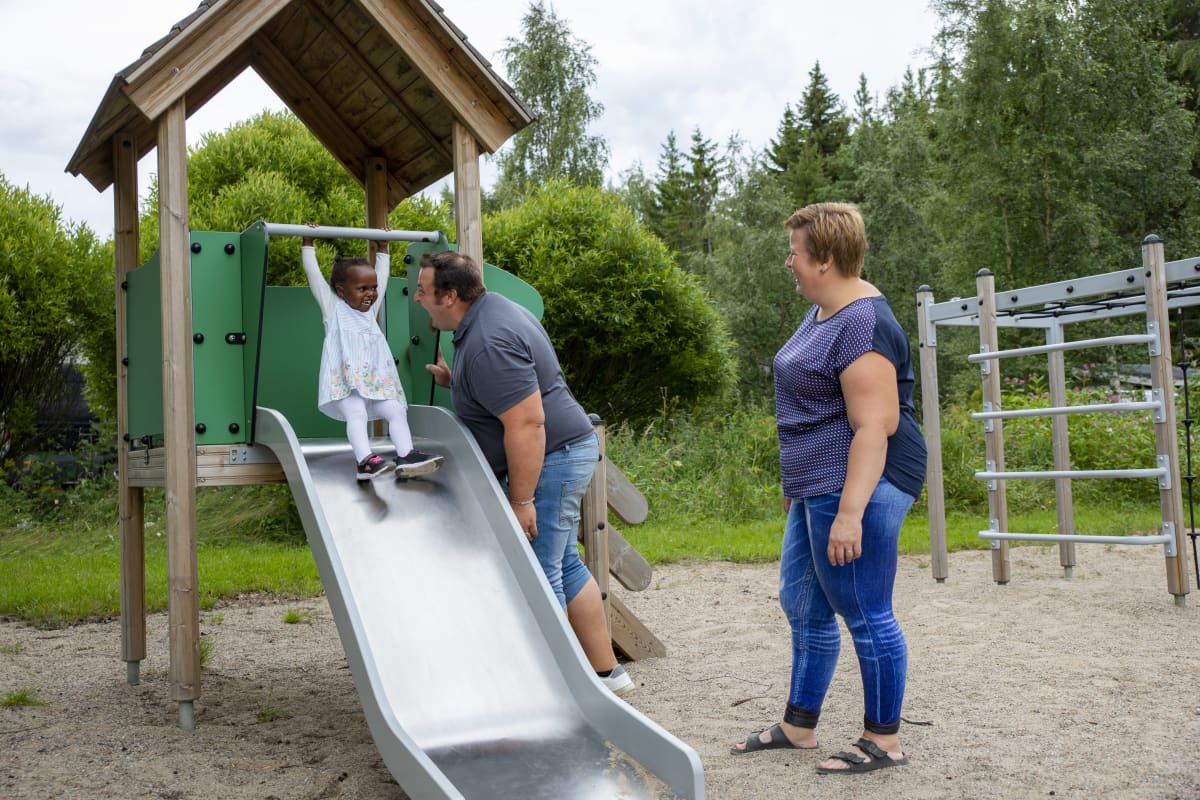 lapsi laskee liukumäestä ja vanhemmat katsovat