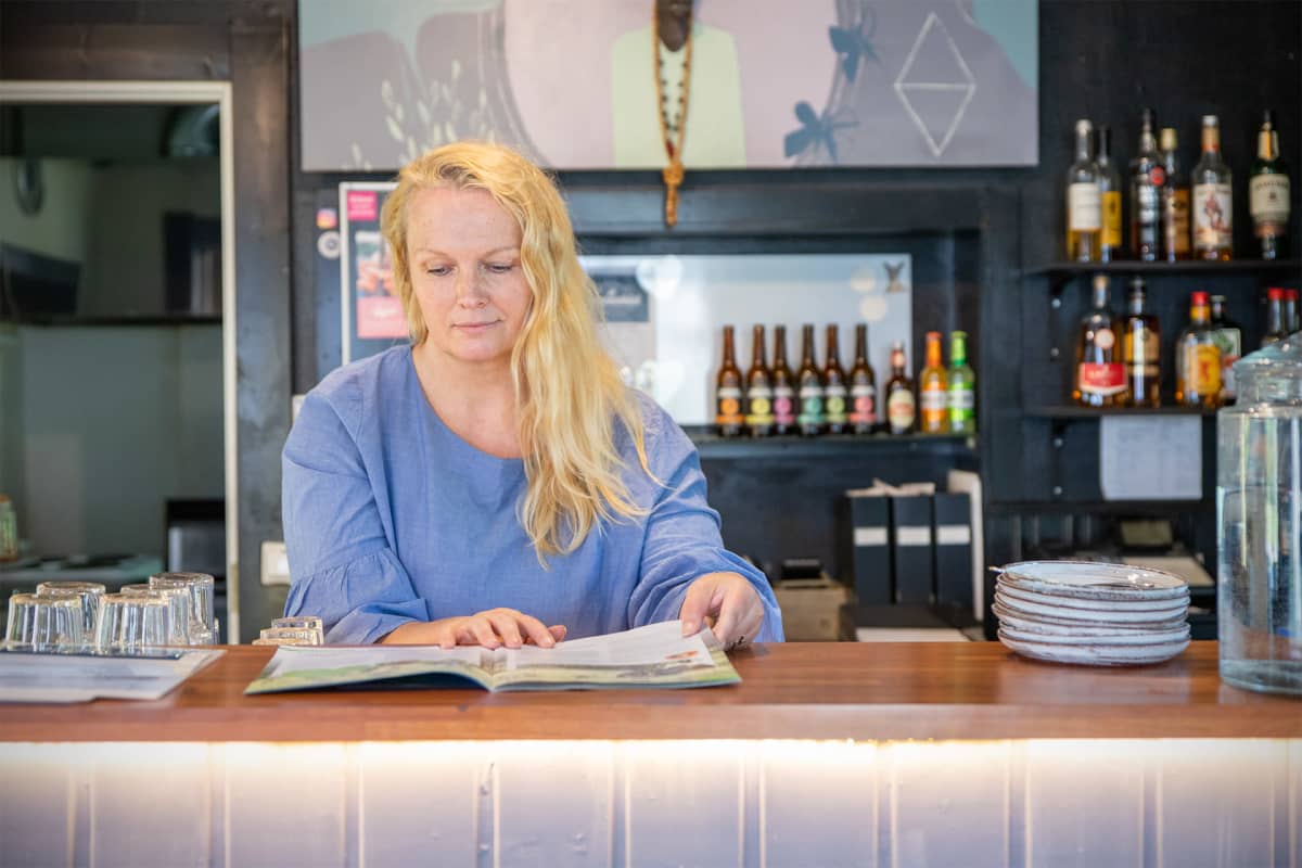 Anne Hakkarainen selaa mainoslehtistä tiskin takana.