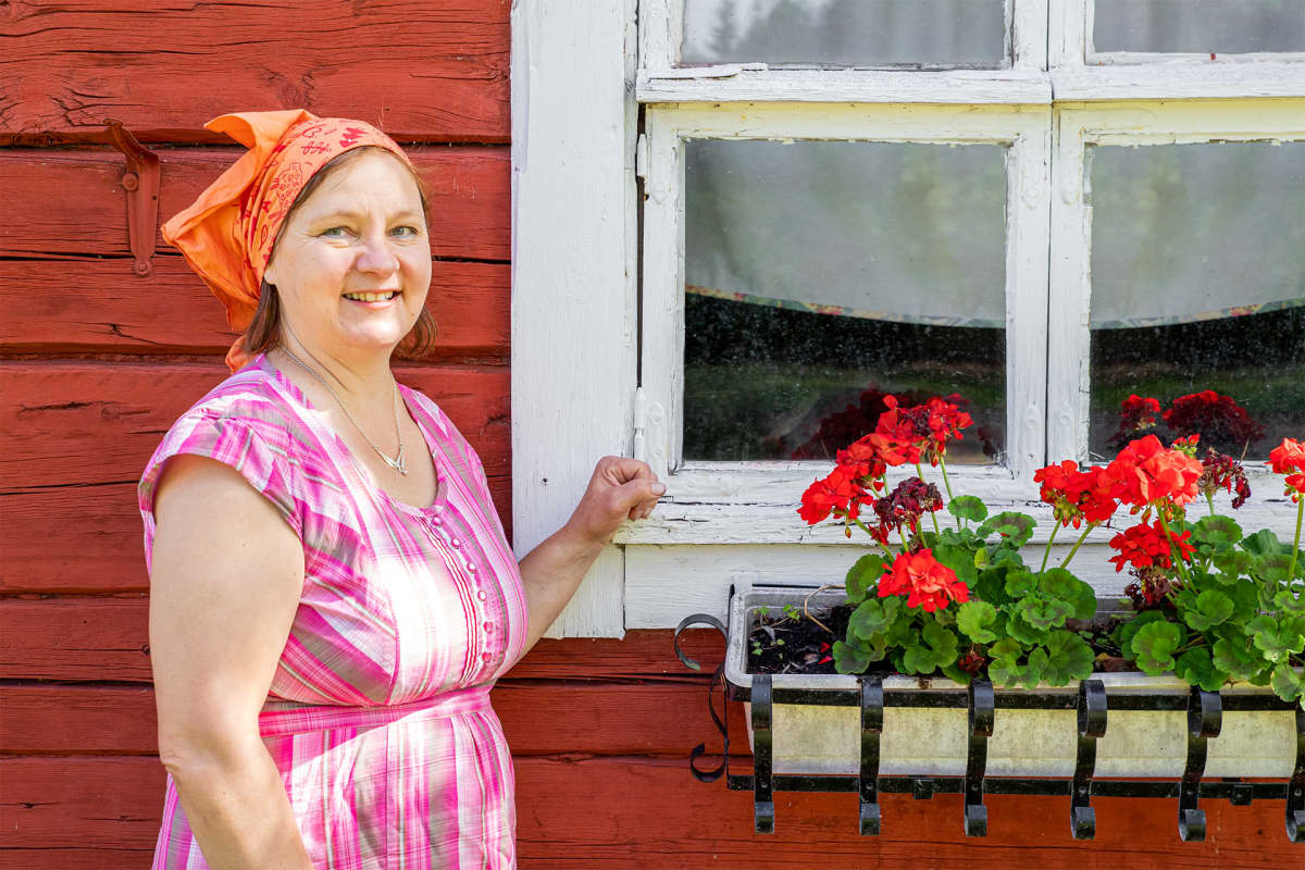 Anne Kalmari poseeraa saunamökin edessä.