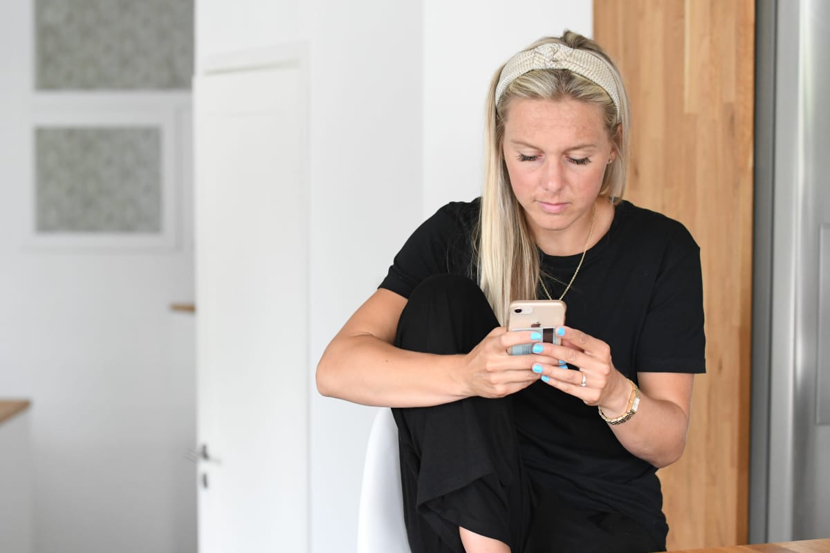 Nina Chydenius kollar sin telefon hemma i köket.