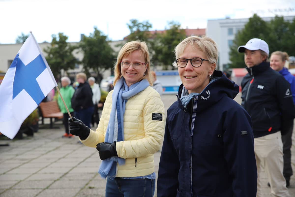 Teija Pääkkönen ja Tuula Rajaniemi seisovat Kokkolan torilla Suomen lippu kädessä
