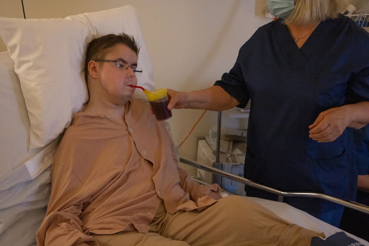 Teemu Puurunen juo pillillä mehua hoitajan avustuksella.