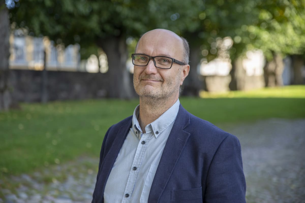 Kylmäliikkeiden liiton toimitusjohtaja Mika Kapanen seisoo vanhojen lehmusten alla ja katsoo kameraan.