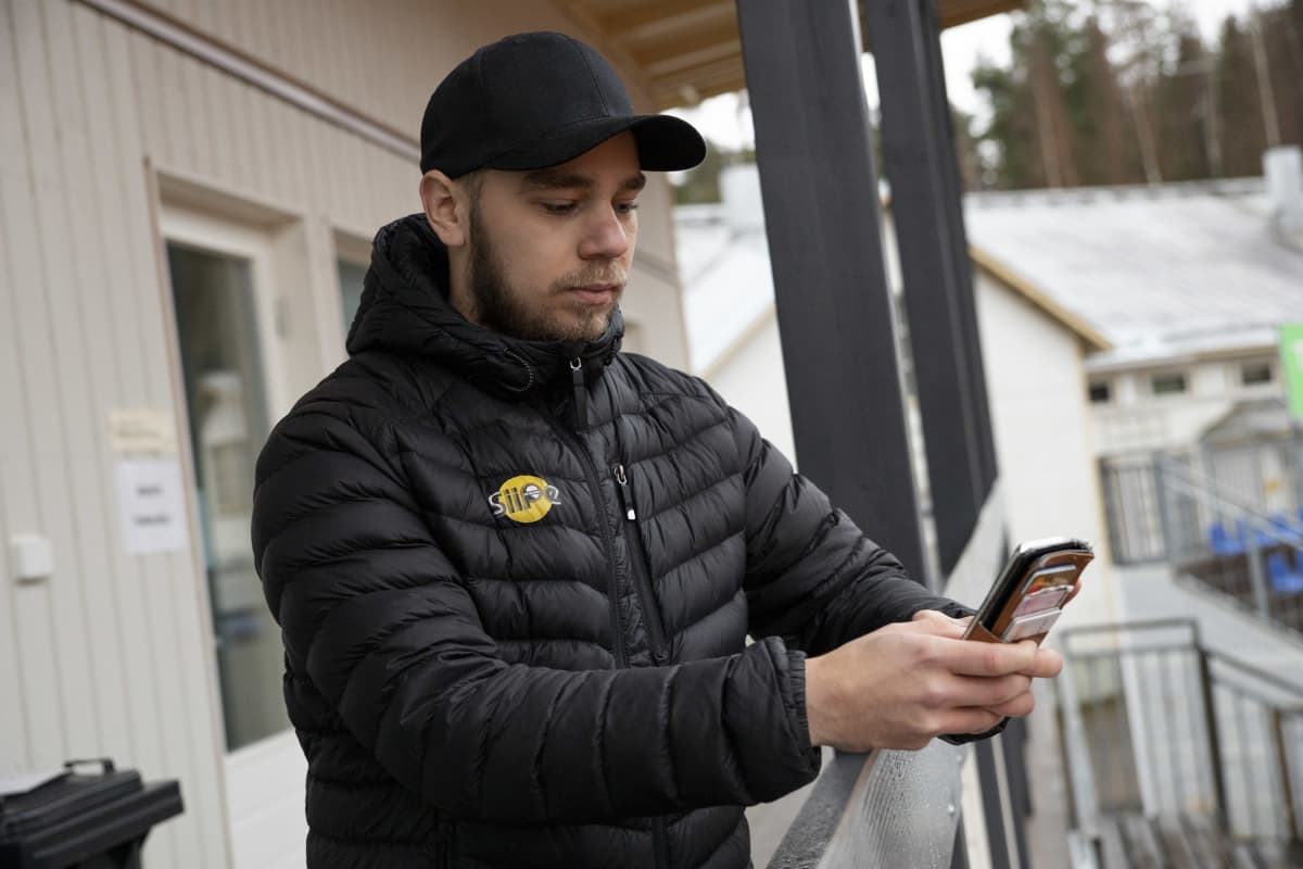 SiiPen pelaaja Eemeli Paldanius selaa kännykkää pesäpallostadionilla Siilinjärven Mantulla.