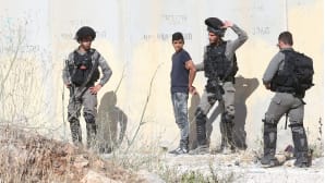 Israelilaiset sotilaat pidättämässä palestiinialaispoikaa.