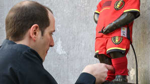 Mies pukee Belgian jalkapallomaajoukkueen uuden peliasun Manneken Pis -patsaalle Brysselissä.