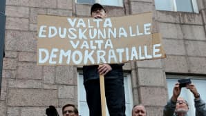 mies pitelee mielenosoituksessa plakaatia