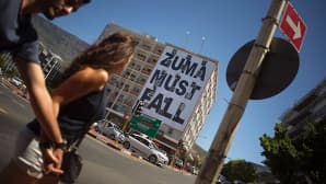 Nuori pari kävelee trendikästä Long street -katua pitkin Etelä-Afrikan Kapkaupungissa. Toisella puolen katua on jättimäinen juliste, jossa lukee ytimekkäästi: "Zuma must fall".