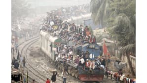 Bangladeshilaiset matkustavat täyteen sullotun junan katolla Dhakassa.