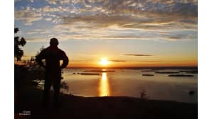 Mies ja auringonnousu Kolin huipulla.