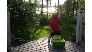 Lapsi katselee terassilta aurinkoiselle järvelle.
