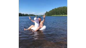 Mies uimassa rantavedessä uimalelun kanssa.