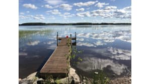 Laituri, tyyni järvi ja pilviä taivaalla.