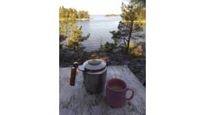 Kahvipannu, kuppi ja saaristomaisema.