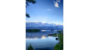 Aurinko alkaa nousta saaren ja pilvien takaa. Syvänsininen taivas.