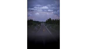 Horisontissa, junaradan yllä, näkyy tummansinisiä ja purppuraisia pilviä.