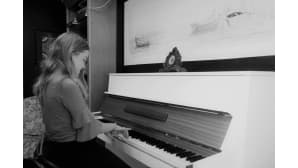 Tyttö soittaa pianoa mustavalkoisessa valokuvassa.