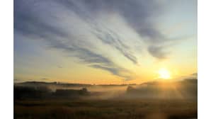 Aurinko nousee sumun takaa.