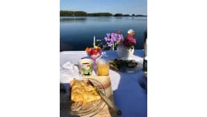 Aamiainen laiturilla. Aurinko paistaa ja sininen on taivas Kouvolan Vuohijärvellä.
