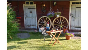 Kuvan aitan seinässä on vuosiluku 1906. Aittaa on käytetty ruoka- ja vilja-aittana sekä yöpymiseen. Aittojen edessä on kaksi vanhaa puista kärrynpyörää sekä puutarhatonttu.