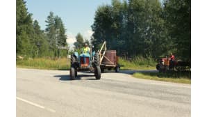 Polovelan papattajien traktori, jonka perässä kulkee pesupalju, jatkamassa matkaa Martonvaaran kesäkahvilan pihasta.