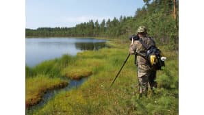 Luontokuvaaja kuvaamassa järven rannalla