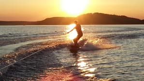 Poika harrastaa wakeboardausta auringonlaskussa