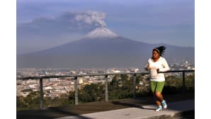 Nainen juokulenkillä Pueblassa, Meksikossa. Taustalla purkautuu tulivuori Popocatepetl.