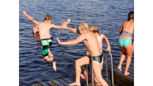 Poikia ja tyttöjä vesileikeissä laiturilla