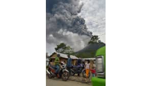 Paikalliset asukkaat pakenevat purkautuvan Sinabung-tulivuoren syöksemien kivenlohkareiden ja tuhkapilven alta.