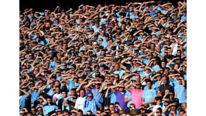 Manchester Cityn kannattajat suojaavat silmiään auringolta paikalliskamppailussa Manchester Unitedia vastaan Etihad-stadionilla.