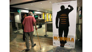 Mies saapuu kävellen kävelykeppi apunaan Mandela: Long Walk to Freedom -elokuvan ensi-iltaan Etelä-Afrikan Johannesburgissa.