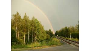 Sateenkaari laskee junaradalle metsämaisemassa