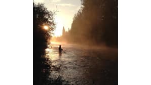 Mies kalastaa joessa auringon laskiessa
