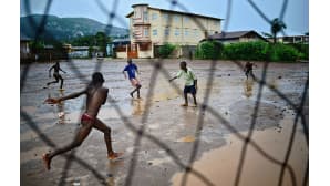 Nuorukaiset pelaavat jalkapalloa sateessa Freetownissa 13. elokuuta 2014. Maailman terveysjärjestö WHO:n mukaan Ebola-virukseen on menehtynyt Guinean, Sierra Leonen, Liberian and Nigerian alueella jo yli 1000.