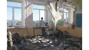 Ukrainalainen sotavanki raivaa tuhoutunutta koululuokkaa.