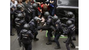 Espanjalaiset mellakkapoliisit poistivat nuoren naisen Ramon Lull koulun äänestyspaikalta 1. lokakuuta Barcelonassa.