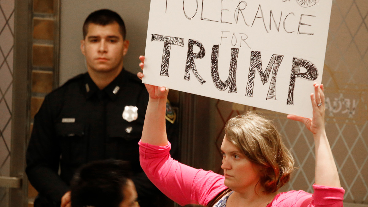 Nainen pitelee kylttiä, jossa lukee "zero tolerance Trump".