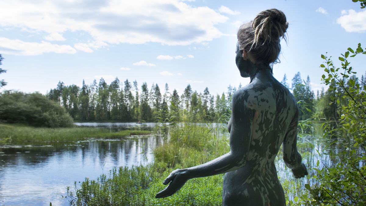 Nainen savikylvyssä keskisuomalaisen järven rannalla.