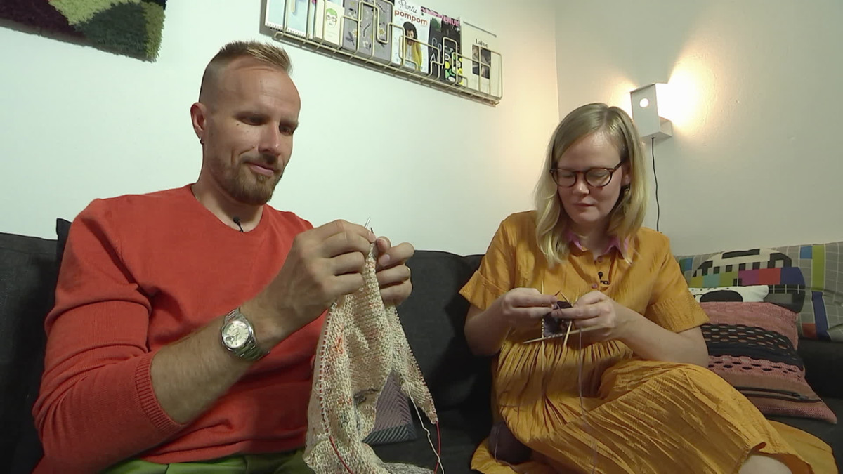 Kaksi ihmistä istuu sohvalla neulomassa