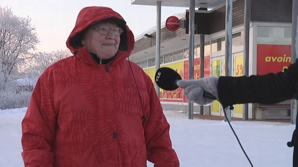 Punaiseen takkiin pukeutunutta naista haastatellaan.