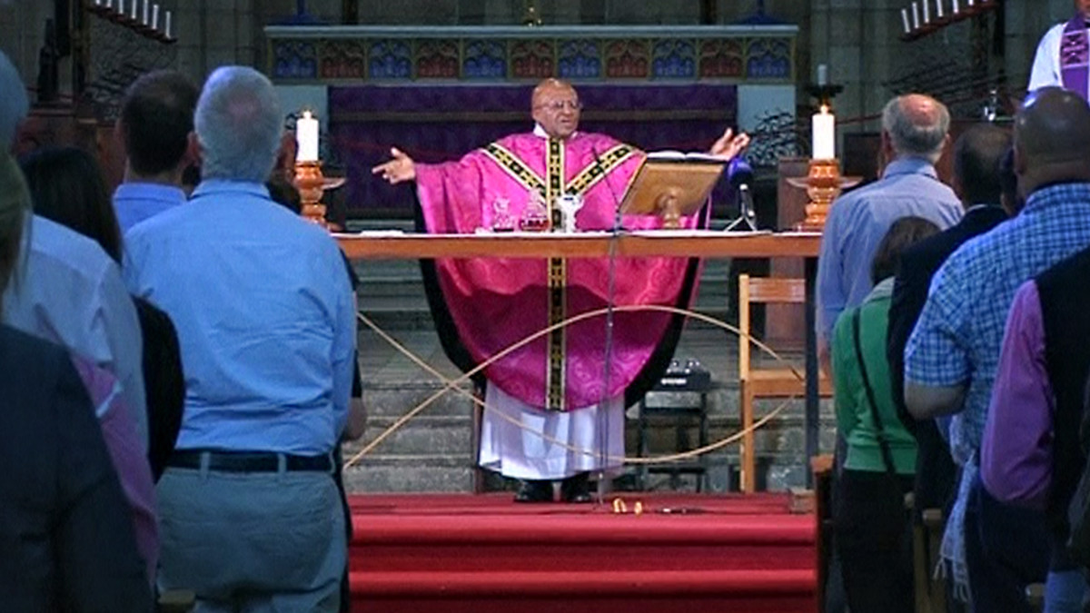 Arkkipiispa Desmond Tutu on levittänyt kätensä alttarilla.