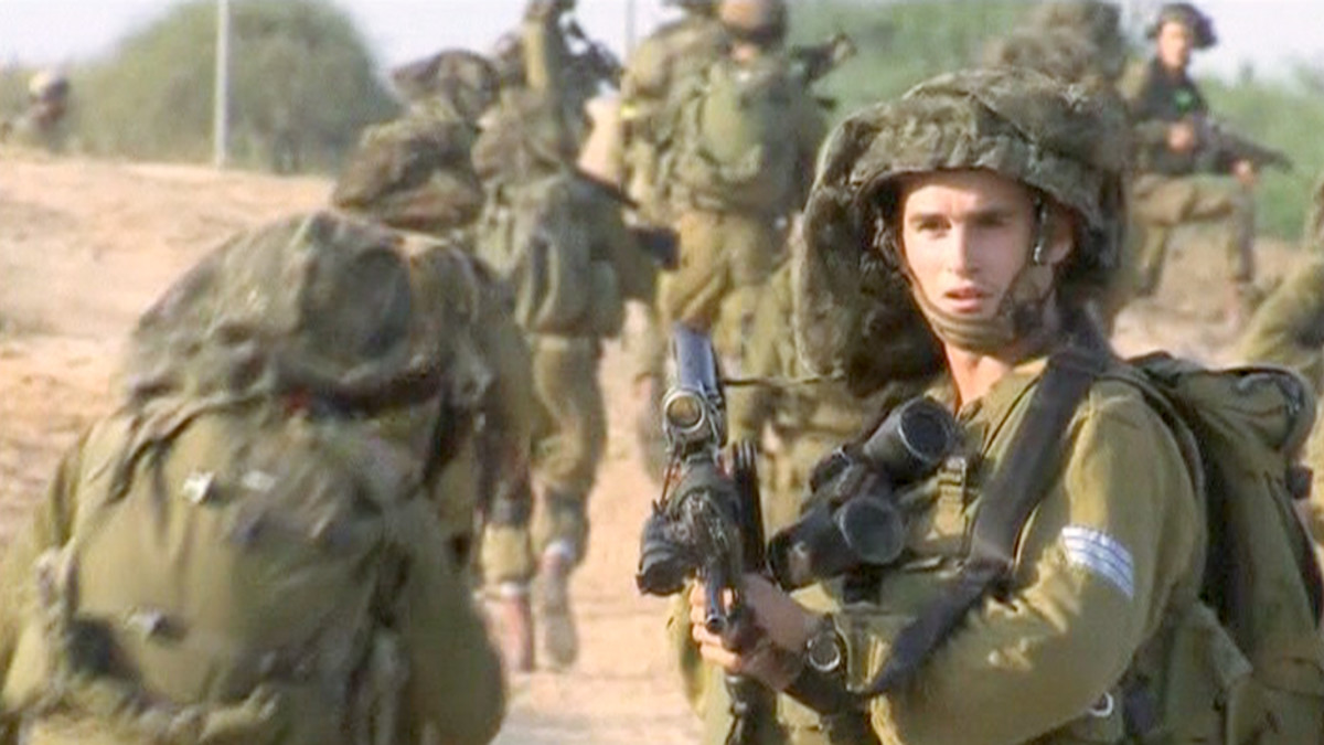Israelilaissotilaita etenemässä Israelin ja Gazan rajalla.